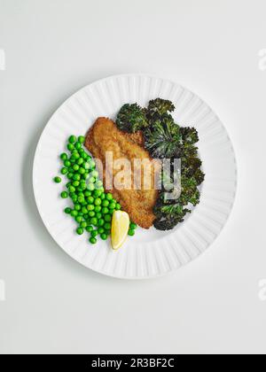 Fischschnitzel mit Grünkohl-Chips und Erbsen Stockfoto