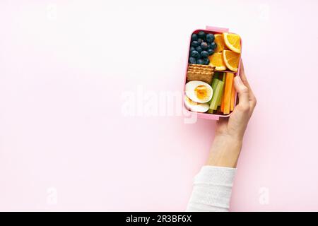 Eine Frau, die eine Lunchbox mit einer gesunden nahrhaften Mahlzeit hält Stockfoto