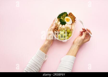 Eine Frau, die eine Lunchbox mit einer gesunden nahrhaften Mahlzeit hält Stockfoto