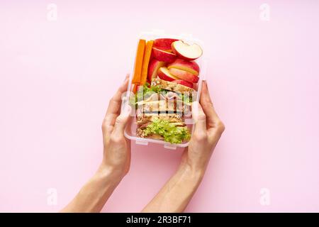 Eine Frau, die eine Lunchbox mit einer gesunden nahrhaften Mahlzeit hält Stockfoto