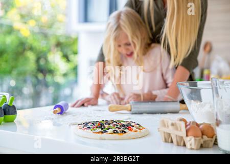 Frische Pizza mit Mutter und Tochter in der Küche zu Hause Stockfoto