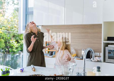 Verspielte Tochter, die sich mit Mutter in der Küche zu Hause amüsiert Stockfoto