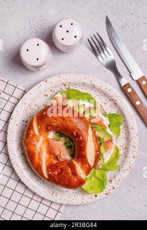 Bagel mit Frischkäse, Salat, geräuchertem Lachs und Avocado Stockfoto