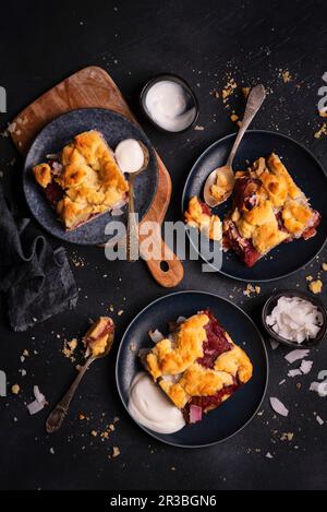 Portionen von Shortbread mit Kokospflaumen und Crumble serviert mit natürlichem Joghurt Stockfoto