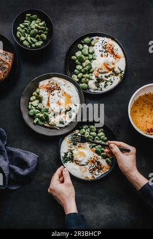 Türkische Eier mit dicken Bohnen mit Dill und schwarzem Kreuzkümmel und Brotscheiben Stockfoto