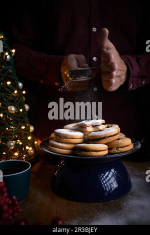 Frisch gebackene Linzer-Kekse, die mit Zucker gefüllt werden Stockfoto