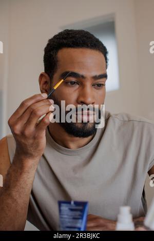 Ein Mann, der zu Hause einen Augenbrauenstift benutzt Stockfoto