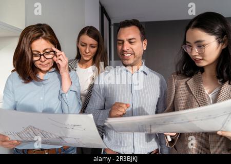 Geschäftsleute, die im Büro stehen und Architekturpläne haben Stockfoto