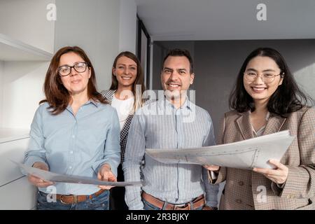 Selbstbewusste Geschäftsleute, die im Büro stehen und Architekturpläne haben Stockfoto