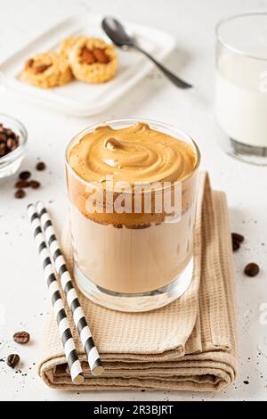 Dalgona-Kaffee in einem transparenten Glas mit Strohhalmen auf einer Serviette Stockfoto