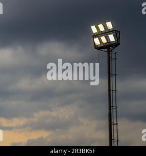 Helle Sportstadion-Lichter an einem bewölkten Abend Stockfoto