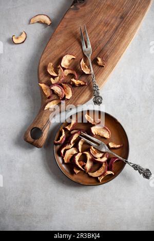 Getrocknete Apfelscheiben auf einem Teller und einem Holzbrett Stockfoto