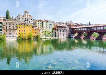 Italien, Venetien, Bassano del Grappa, Fluss Brenta mit Gebäuden und Ponte Vecchio im Hintergrund Stockfoto