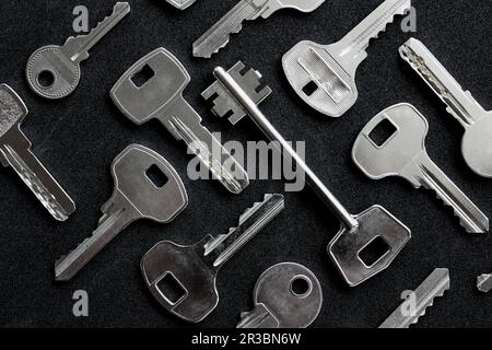 Ein Muster verschiedener Schlüsseltypen aus Schlössern, die auf der schwarzen Oberfläche angeordnet sind, Draufsicht Stockfoto