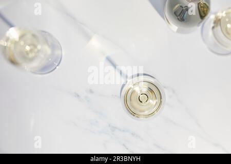 Drei Weißweingläser und eine Weißweinflasche auf einem Marmorteller Stockfoto