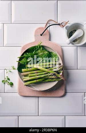 Grüner Spargel und frischer Spinat in einer Keramikschüssel Stockfoto