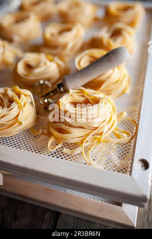 Frische Linguine in Nestern auf Trockenregalen Stockfoto