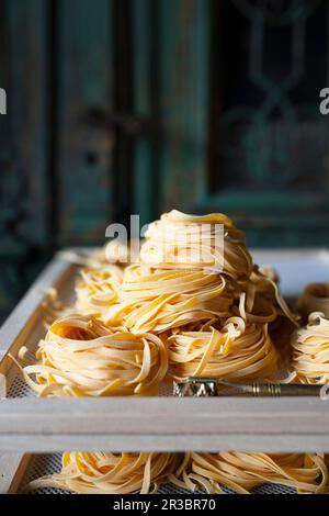 Frische Linguine in Nestern auf Trockenregalen Stockfoto