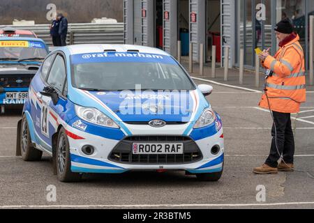 Chris Daykin und Michael Weeks in ihrem Ford Fiesta R2 2011 mit dem Control Point Marshal während der Snetterton Stage Rally 2023, Norfolk, Großbritannien. Stockfoto