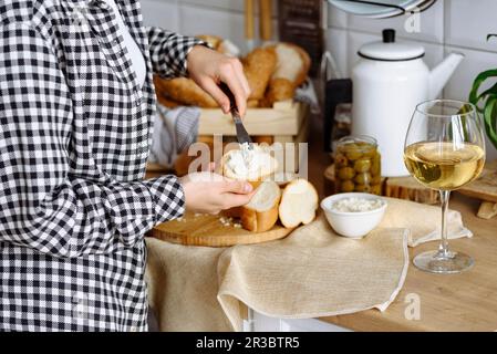 Die Frau in der Küche macht Sandwiches aus Baguette und Frischkäse Stockfoto