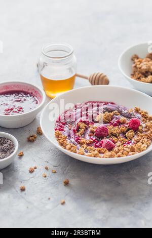 Müsli mit Beerenjoghurt, Honig, Chiasamen, Himbeersauce und frischen Himbeeren Stockfoto