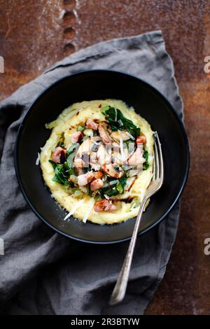 Polenta mit Mangold, Pilzen, Speck und Parmesan Stockfoto