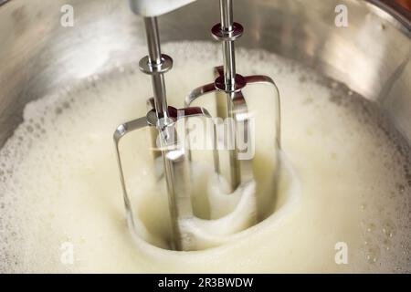 Eiweiß mit einem Handmixer verprügeln, bis es steif ist Stockfoto