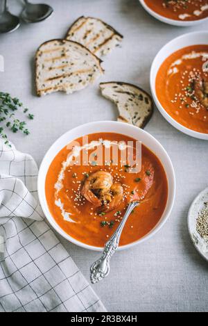 Süße Pfeffer- und scharfe Garnelensuppe serviert mit getoastetem Brot auf Leinentuch Stockfoto