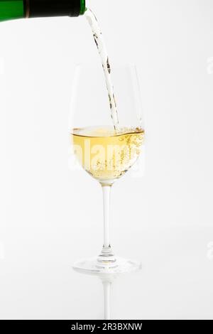 Weißwein wird aus einer Flasche in ein Glas gegossen Stockfoto