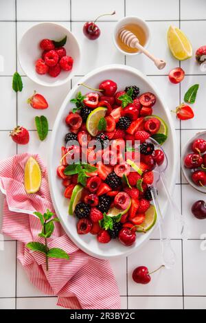 Obstsalat mit Erdbeeren, Kirschen, Brombeeren, Himbeeren Limette und frischer Minze Stockfoto