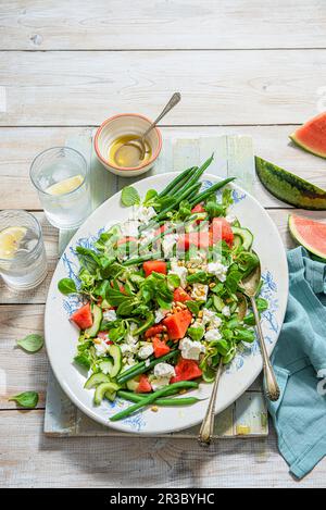 Sommersalat mit Wassermelone, Feta, Bohnen, Gurke, Pinienkernen und Olivenöl Stockfoto