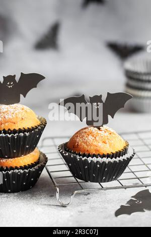 Halloween-Kürbis-Muffins in schwarzen Kapseln, dekoriert mit Fledermäusen aus Pappe. Festlicher Halloween-Cupcake Stockfoto