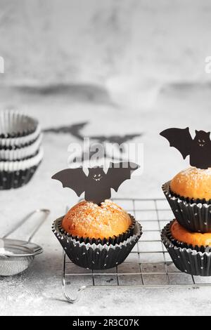 Halloween-Kürbis-Muffins in schwarzen Kapseln, dekoriert mit Fledermäusen aus Pappe. Festlicher Halloween-Cupcake Stockfoto