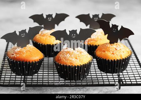 Halloween-Kürbis-Muffins in schwarzen Kapseln, dekoriert mit Fledermäusen aus Pappe. Festlicher Halloween-Cupcake Stockfoto