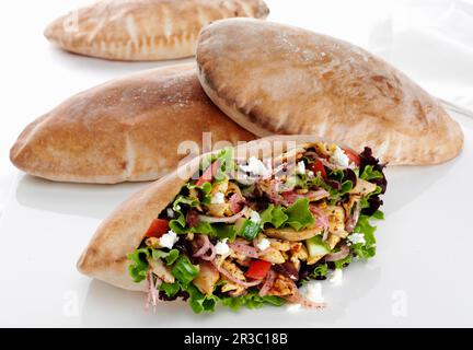 Pita-Tasche gefüllt mit mediterranem gewürztem Hähnchen, Salat, Gurke, Tomaten, Sumac-Zwiebeln, Fetakäse und schwarze Oliven Stockfoto