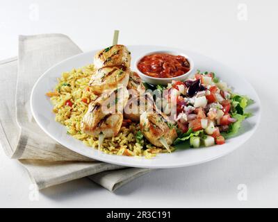 Hähnchen-Kabobs auf mediterranem gelben Reis, griechischem Salat und Harrisa-Sauce Stockfoto