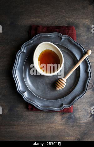 Keramikschüssel mit biologischem Sommerhonig und Holzlöffel Stockfoto