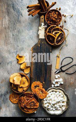 Getrocknete Früchte, Mini-Marshmallows und Zimtstangen auf altem Holzbrett Stockfoto