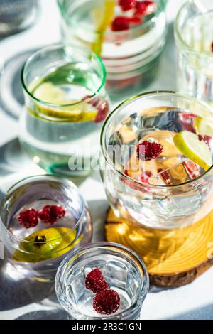 Gläser mit Zitronen- und Beerenwasser auf Betonhintergrund Stockfoto