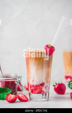 Iced Flat White mit Erdbeere und Erdbeersauce, serviert in einem Glas Stockfoto