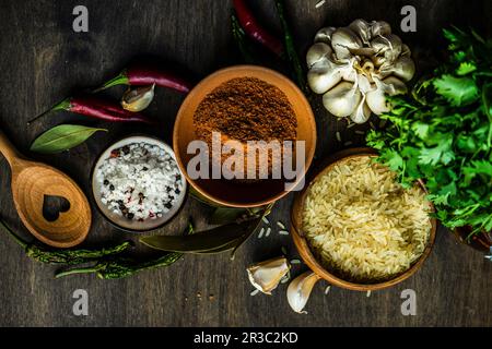 Traditionelles georgianisches Gewürz zum Kochen von Pilaf in einer Schüssel in der Nähe einer Reisschüssel auf einem Holztisch Stockfoto