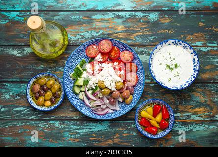 Griechischer mediterraner Salat mit Tomaten, Fetakäse und Gurke auf dem Teller und verschiedenen traditionellen Vorspeisen Stockfoto