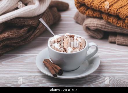 Heiße Schokolade mit Marshmallow und ein Haufen warmer Strickkleidung Stockfoto