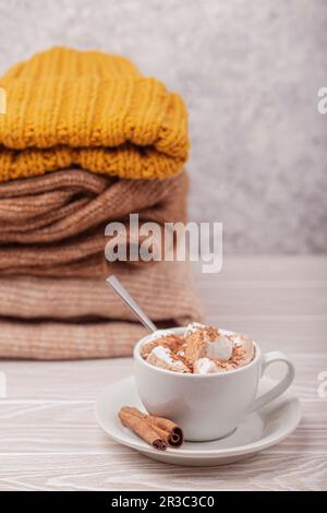 Heiße Schokolade mit Marshmallow und ein Haufen warmer Strickkleidung Stockfoto
