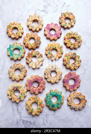 Vegane Kekse mit kurzer Kruste, gefüllt mit Marmelade und farbenfrohen Zuckerdekorationen Stockfoto