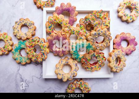 Vegane Kekse mit kurzer Kruste, gefüllt mit Marmelade und farbenfrohen Zuckerdekorationen Stockfoto