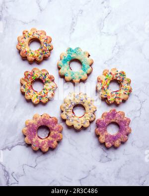 Vegane Kekse mit kurzer Kruste, gefüllt mit Marmelade und farbenfrohen Zuckerdekorationen Stockfoto