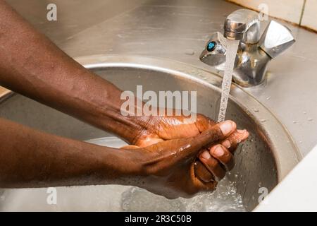 Afrikanische Person wäscht sich die Hände im Becken, um sich vor der Ausbreitung des Virus zu schützen Stockfoto