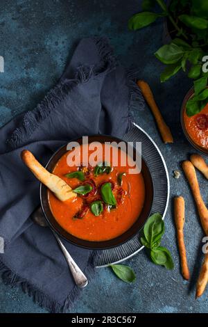 Tomatensuppe mit gerösteten Kirschtomaten, Basilikum und Brotstangen Stockfoto