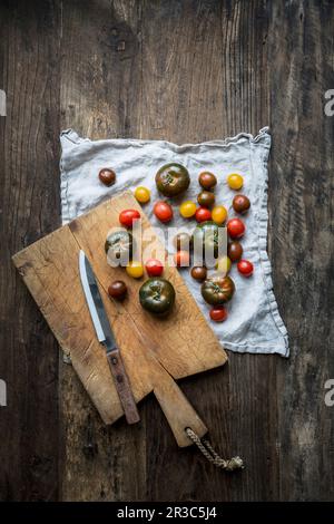 Gemischte Sorten gewaschener Tomaten auf einem Leinentuch mit Schneidebrett Stockfoto